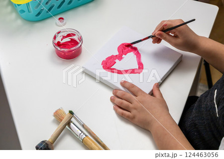 The child paints a red heart 124463056