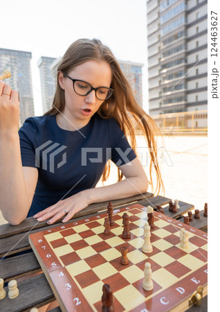 Caucasian woman playing chess outdoors. 124463627