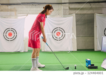 室内ゴルフ練習場で練習をする女性 124464801
