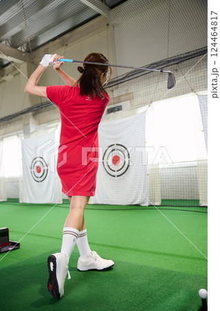室内ゴルフ練習場で練習をする女性 124464817