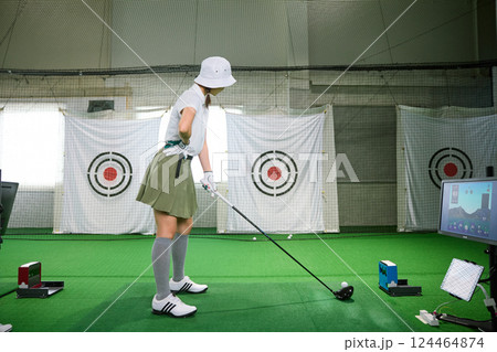 室内ゴルフ練習場で練習をする女性 124464874