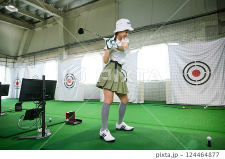 室内ゴルフ練習場で練習をする女性 124464877