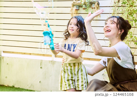 庭で電動シャボン玉を使って遊ぶ親子 124465108