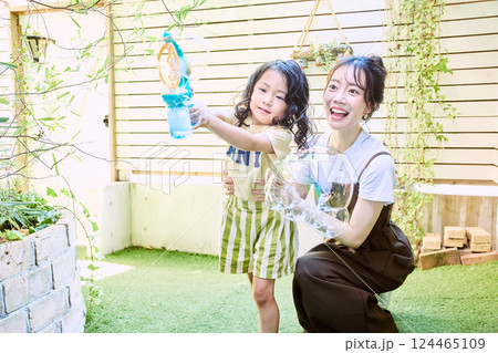 庭で電動シャボン玉を使って遊ぶ親子 124465109