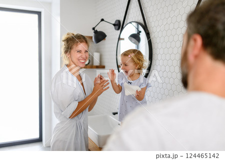 Parents and daughter having morning bathroom routine, brushing teeth and washing face, enjoying together time. Parents and daughter having morning bathroom routine, brushing teeth and washing face, enjoying together time. 124465142