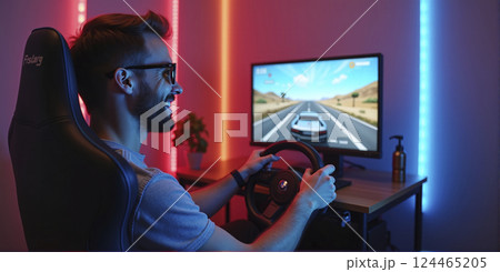 Gamer playing a car racing simulation at home with a steering wheel controller and having fun, e-sports and gaming industry Gamer playing a car racing simulation at home with a steering wheel controller and having fun, e-sports and gaming industry 124465205