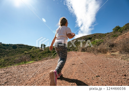 Caucasian young girl hiking on trail under blue sky in nature 124466036
