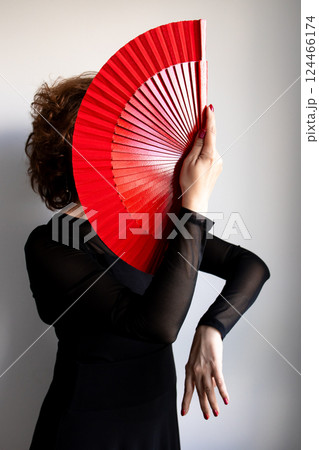 Female dancer with red fan in elegant black attire 124466174