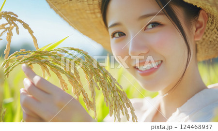 稲穂を手に微笑む麦わら帽子の日本人女性 124468937