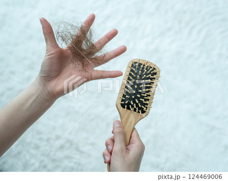 Someone holding a comb with hair loss after brushing hair. Someone holding a comb with hair loss after brushing hair. 124469006