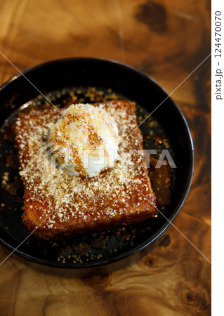 Fresh bread butter toast with Vanilla flavor ice cream on black ceramic plate on wooden table. 124470070