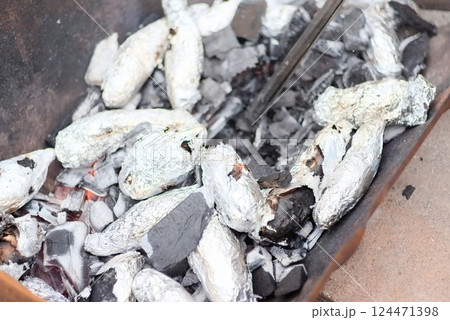 炭火の中に投入されたアルミホイルに包まれたさつまいも 124471398