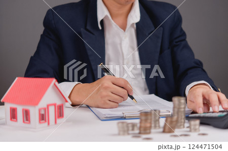 Loan documents and finance agreement on table near home model for ownership planning. Buying or selling a house involves money management and legal agreements for secure deals and insurance Loan documents and finance agreement on table near home model for ownership planning. Buying or selling a house involves money management and legal agreements for secure deals and insurance 124471504
