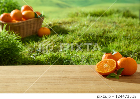 The light-grained wooden floor has fresh oranges with intact stems and rough skin. Orange segment is shiny and juicy in the sunlight. Basket of Citrus is placed on the green grass in the garden. 124472318