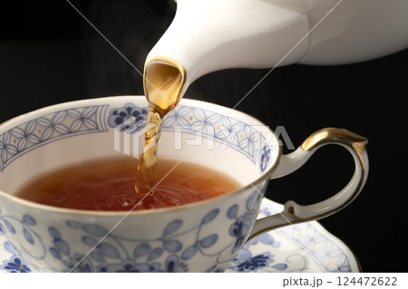 ティーポットでティーカップに紅茶を注ぐ ティーポットでティーカップに紅茶を注ぐ 124472622