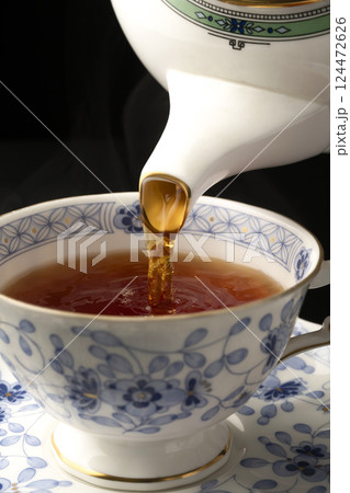 ティーポットでティーカップに紅茶を注ぐ ティーポットでティーカップに紅茶を注ぐ 124472626
