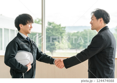 会議室で握手する作業服姿の若いアジア人男性 会議室で握手する作業服姿の若いアジア人男性 124474088