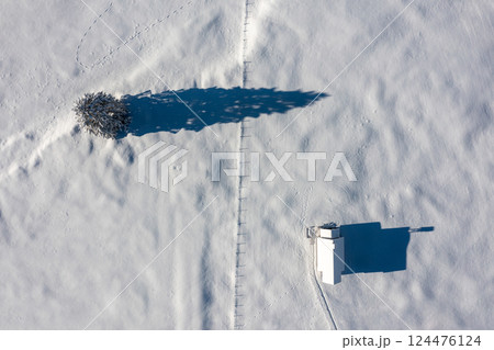 Snowy church minimalist on a snow-covered valley, winter aerial view in the Bavarian Alps, Germany 124476124