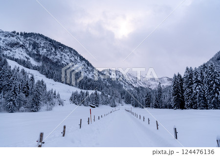 Snow-covered road passing through an alpine valley in the Bavarian Alps, Germany 124476136