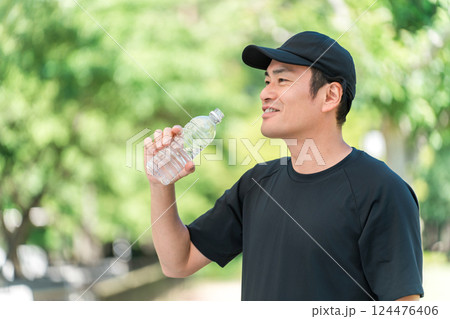 運動中に水・ミネラルウォーターを飲む男性（水分補給・運動・ワークアウト・ランニング・ウォーキング） 124476406