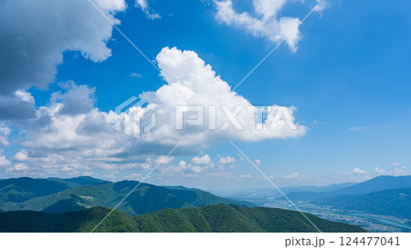 青空に流れるたくさんの白い雲と、緑に包まれた山々 青空に流れるたくさんの白い雲と、緑に包まれた山々 124477041