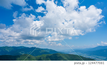 青空に流れるたくさんの白い雲と、緑に包まれた山々 124477081