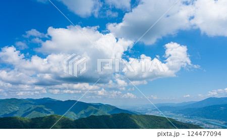 青空に流れるたくさんの白い雲と、緑に包まれた山々 青空に流れるたくさんの白い雲と、緑に包まれた山々 124477094