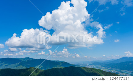 青空に流れるたくさんの白い雲と、緑に包まれた山々 124477134