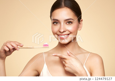 Beautiful young woman brushing her teeth 124479127