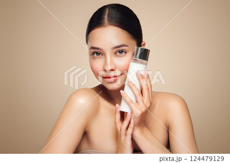 Smiling woman holds bottle with cosmetic milk 124479129