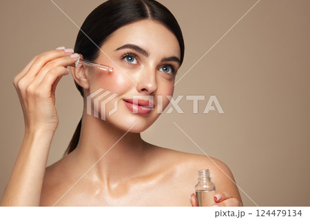 Young beautiful woman applying face serum Young beautiful woman applying face serum 124479134
