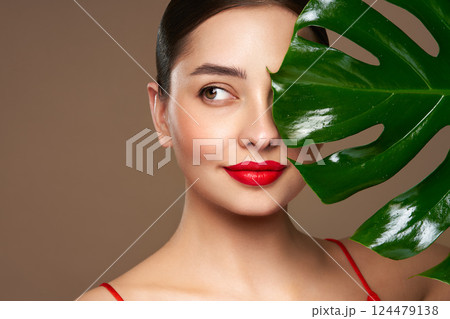 Close up woman face with green exotic leaf 124479138
