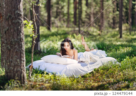 Young woman is reading a book in the forest 124479144