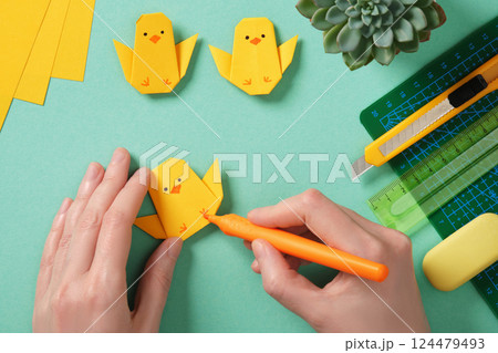 Making a simple Easter origami handicraft. Draw eyes and legs on the finished chicken. Around ready-made crafts chickens and tools for crafts Making a simple Easter origami handicraft. Draw eyes and legs on the finished chicken. Around ready-made crafts chickens and tools for crafts 124479493