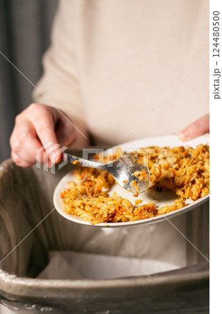 Vertical image of woman throwing away bio trash with food leftovers into garbage. Compost. Environment friendly. Stop food waste day. Vertical image of woman throwing away bio trash with food leftovers into garbage. Compost. Environment friendly. Stop food waste day. 124480500