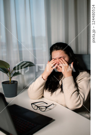 Stressed ang exhausted businesswoman with eye strain removes eyeglasses to reduce eye pain. Overworking concept Stressed ang exhausted businesswoman with eye strain removes eyeglasses to reduce eye pain. Overworking concept 124480514