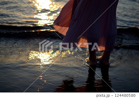 夕暮れの海に佇む足元と波間の光 夕暮れの海に佇む足元と波間の光 124480580