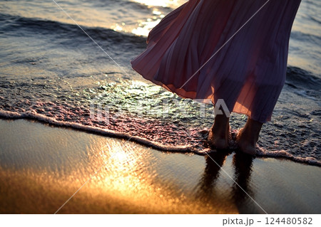 夕暮れの海に佇む足元と波間の光 124480582