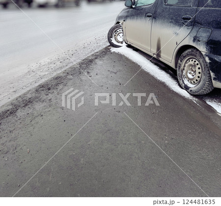 Car with damaged tire on the side of the road on a winter snowy day. The parked vehicle exhibits signs of winter driving challenges in a bustling city environment Car with damaged tire on the side of the road on a winter snowy day. The parked vehicle exhibits signs of winter driving challenges in a bustling city environment 124481635