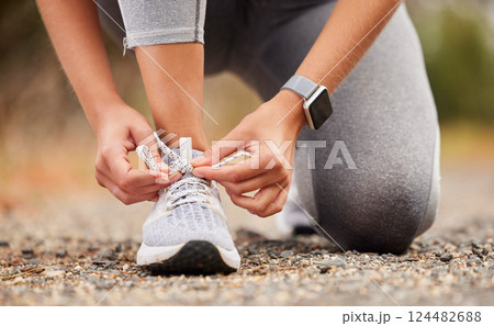Shoes, fitness and exercise with a sports woman tying her laces before training, running or a workout. Hands, health and cardio with a female runner or athlete getting ready for an endurance run 124482688