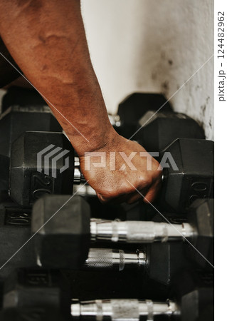 Hand, dumbbell and fitness with a man bodybuilder in a gym for exercise, training or a workout with weights. 124482962