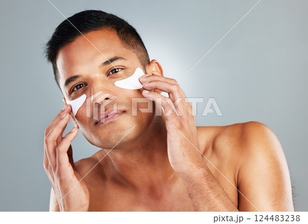 Model, skincare and eye mask for man in portrait for health, wellness and cosmetics with grey backdrop. Face, cosmetic and facial for beauty, self love and self care with studio background for care Model, skincare and eye mask for man in portrait for health, wellness and cosmetics with grey backdrop. Face, cosmetic and facial for beauty, self love and self care with studio background for care 124483238