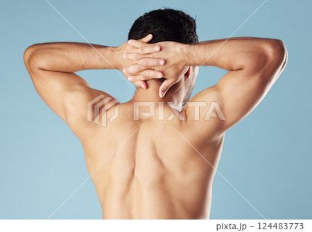 Back, man and muscular body in studio for fitness results, biceps progress and training goals. Bodybuilder, topless and hands on head for flexing, exercise and workout performance on blue background Back, man and muscular body in studio for fitness results, biceps progress and training goals. Bodybuilder, topless and hands on head for flexing, exercise and workout performance on blue background 124483773