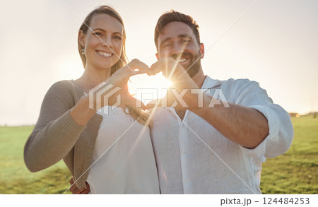 Couple, portrait and heart hand with sun for romantic date on beautiful field in Ireland. Love, happy and smile of dating people enjoying countryside together with natural sunshine flare. 124484253