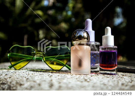 Tropical summer cosmetics. Cosmetic serum, oil extracts against lush greenery of tropics. Skin care products. Beauty nature. Heart-shaped sunglasses. Tropical summer cosmetics. Cosmetic serum, oil extracts against lush greenery of tropics. Skin care products. Beauty nature. Heart-shaped sunglasses. 124484549