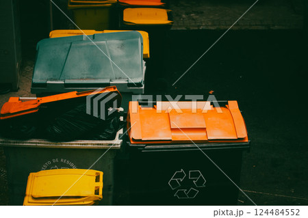 Colorful bright dumpsters for sorting miscellaneous waste in a back yard. Garbage cans for segregating different types of waste materials. Trash can. 124484552