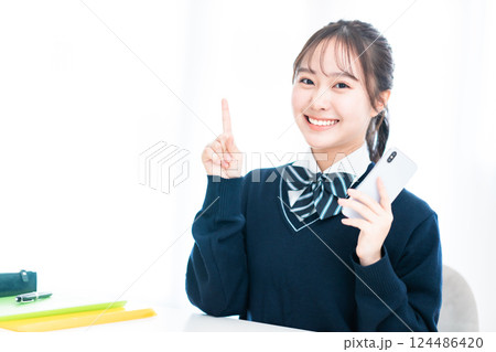 指差しポーズで微笑む女子高生 124486420