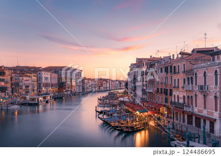 Venice canal at sunset, gondolas moored, cafes open. 124486695