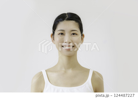 白背景のタンクトップを着た笑顔の若い女性 124487227