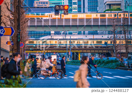 日本の東京都市景観 仕事帰り…大手町駅前の交差点や夕日を浴びる電車などを望む。奥は日本橋… 124488127